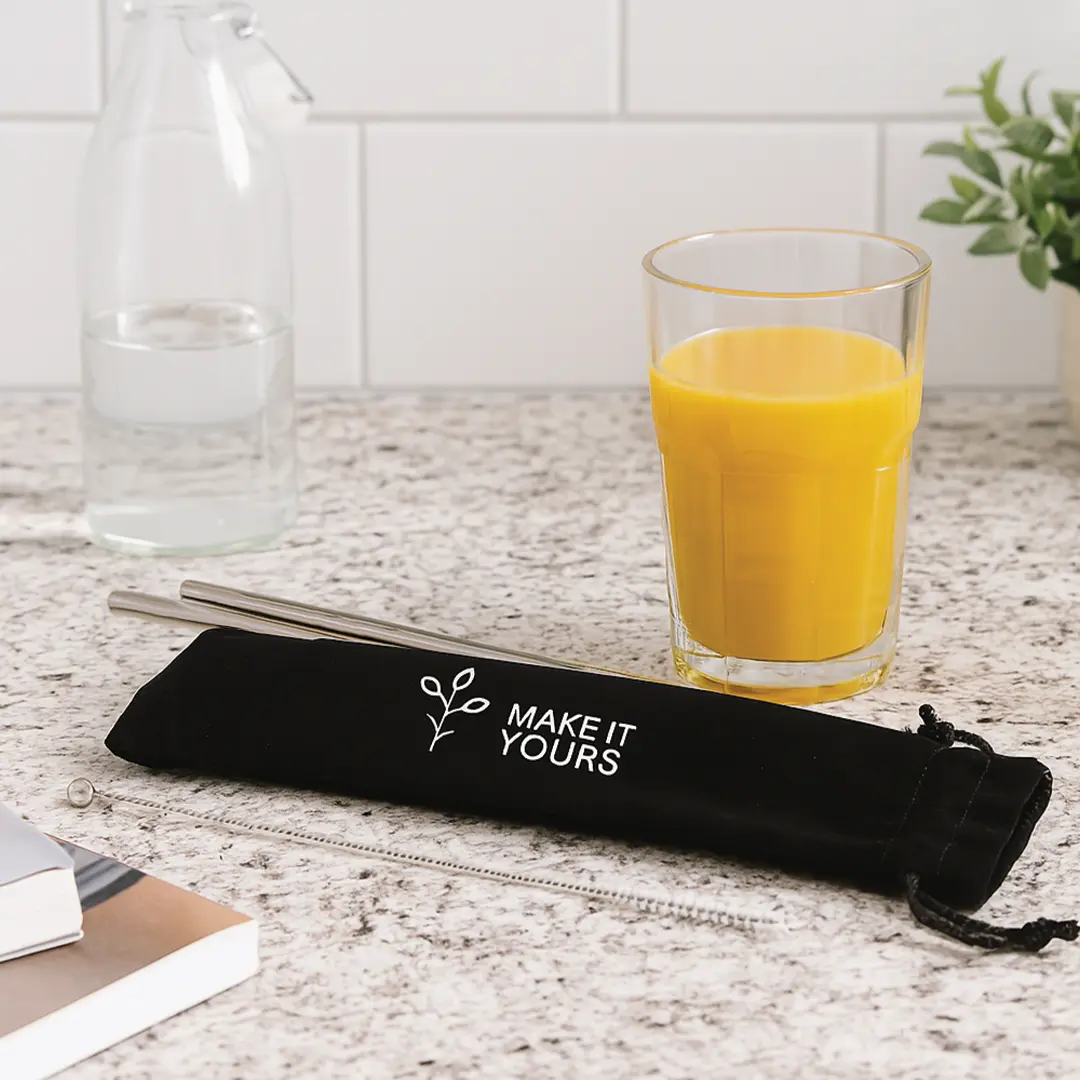 metal straws and pouch laying on kitchen counter beside glass of orange juice