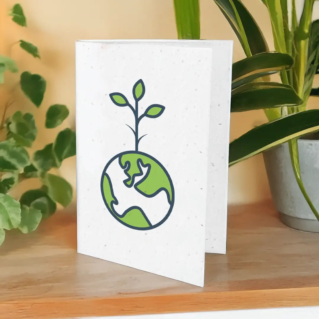 seed paper greeting card standing on wood table surface beside large potted plant