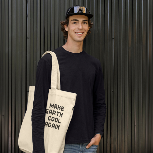 man wearing branded tote bag over shoulder and smiling