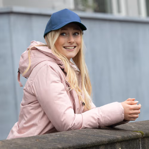 woman smiling wearing ball cap leaning on fence