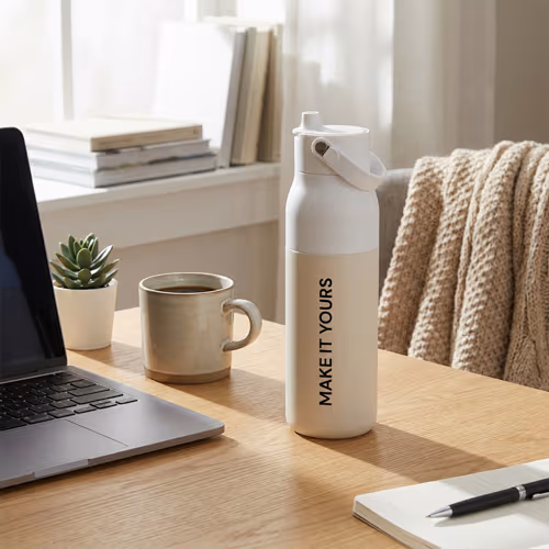 branded water bottle on wooden desk beside bright window