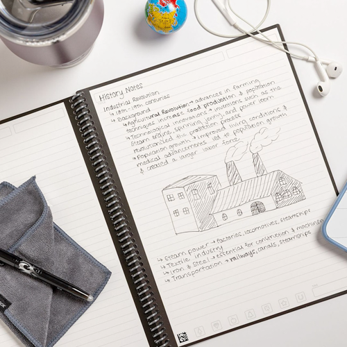 notebook resting on work desk beside wired headphones and pen