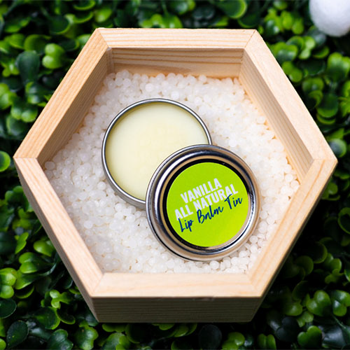 lip balm tin resting in a hexagon wooden box filled with wax pellets