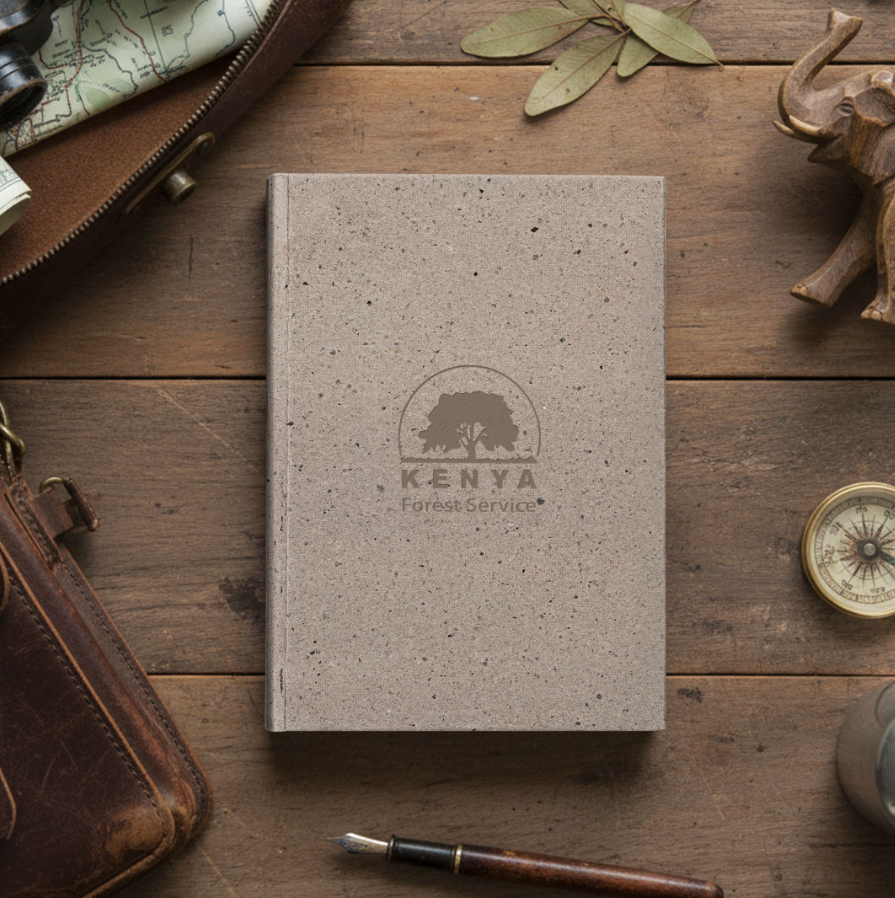 coffee husk notebook resting on dark wood table surrounded by dried leaves and leather satchel