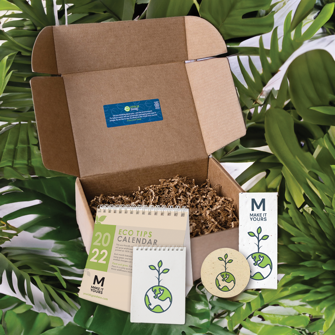 swag pack laying on leaves containing seed paper calendar, seed paper notebook, seed paper coaster and seed paper bookmark