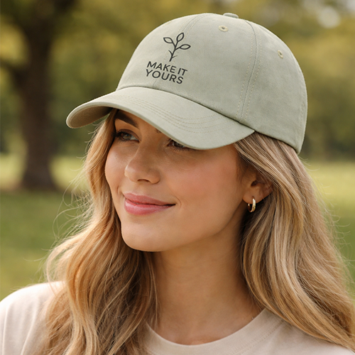 young woman smiling and wearing khaki coloured ballcap with logo embroidered on the front