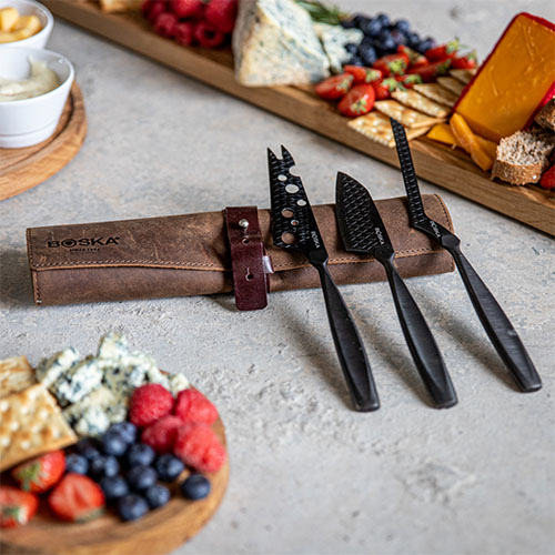 cheese knife set surrounded by cheese and fruit
