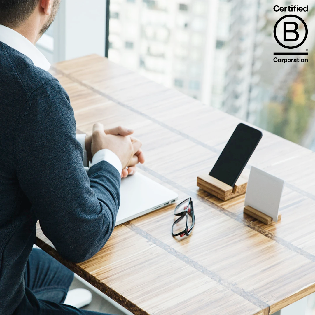 man sitting at work desk with bamboo phone holder in front of him propping up a smartphone